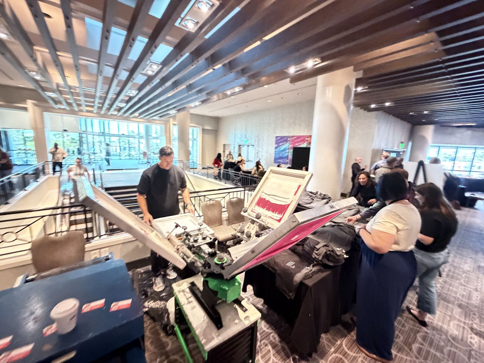 Live printing station at a corporate event with an operator running the press and folded custom apparel for guests